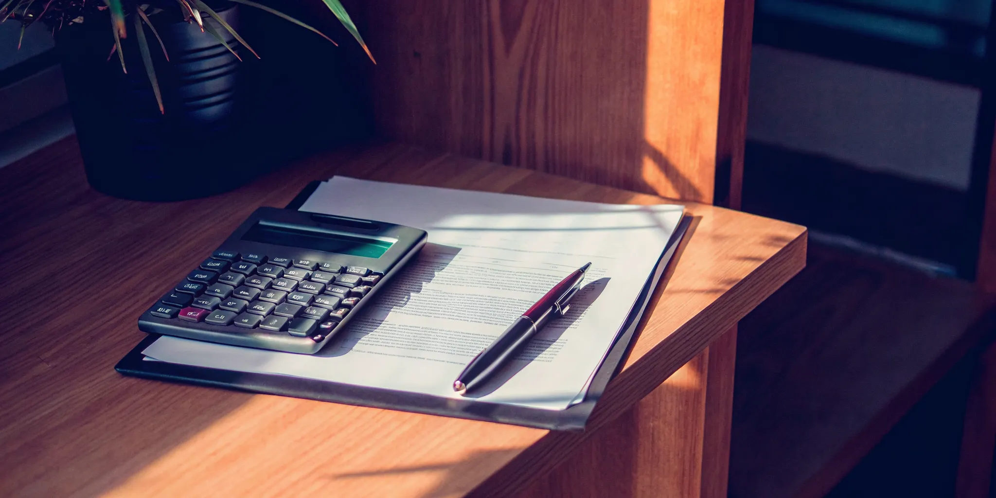 A modern calculator and pen lying on a legal contract on a desk, calculating simple versus compounding interest rates